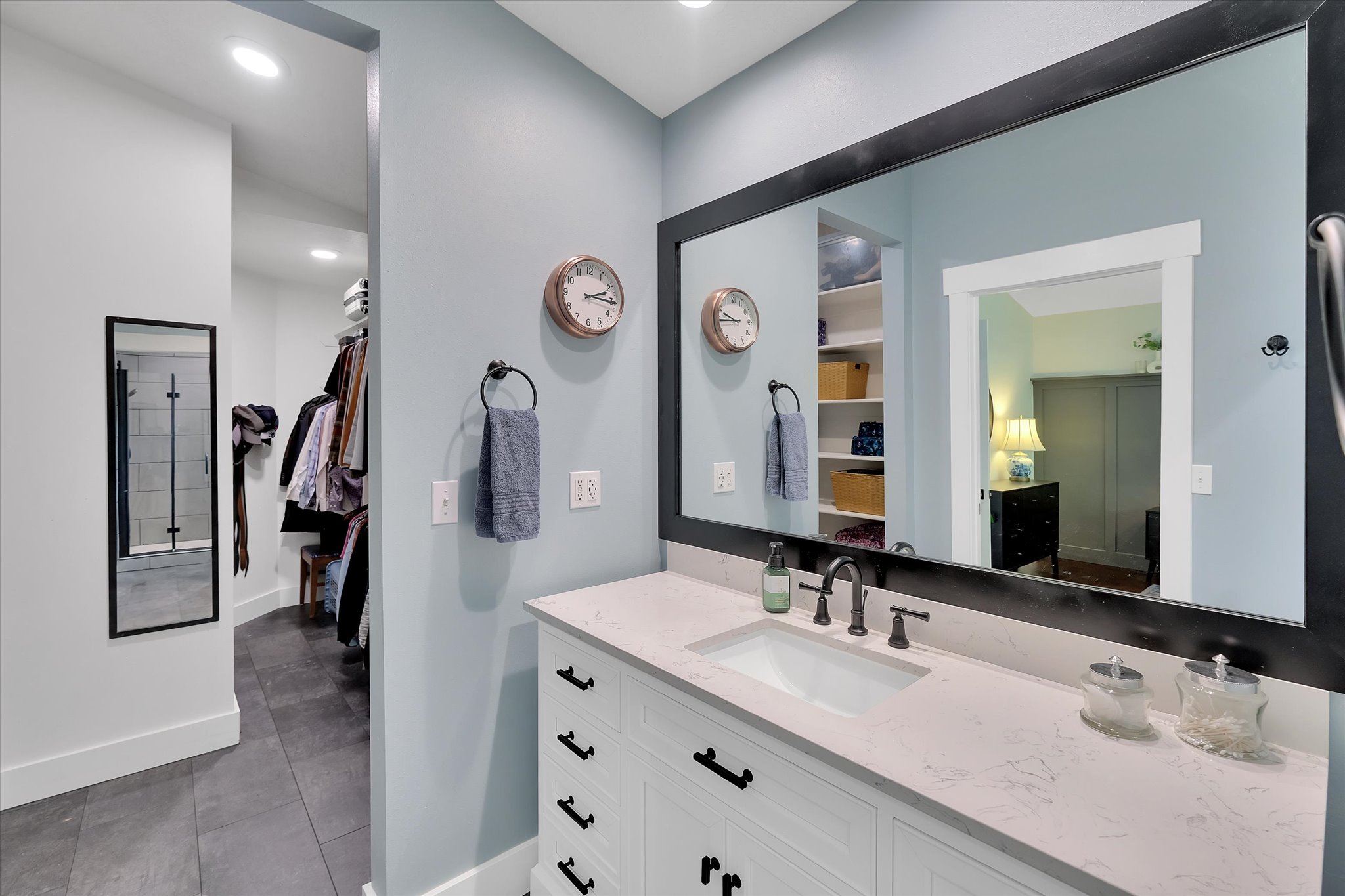 Bathroom vanity featuring a rectangular undermount sink, a light-toned countertop, and white cabinetry with dark hardware
