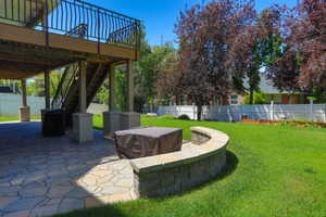 Lower-level patio featuring flagstone pavers, a curvilinear stone retaining wall, and a staircase leading to an upper deck with black iron railings