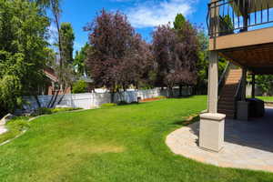 Spacious backyard featuring a multi-level deck with stairs, a flagstone patio, and a manicured lawn