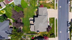 Expansive property featuring a large asphalt shingle roof, concrete driveway, and a spacious green lawn