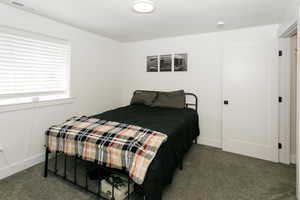 Carpeted room featuring a white window with blinds, white walls, and a recessed light fixture