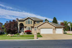 Stucco and brick exterior residence featuring a three-car garage and arched entryway