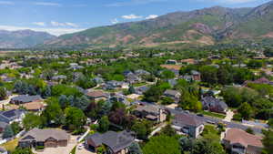 Expansive residential area featuring numerous single-family homes, mature trees, and mountainous terrain in the background