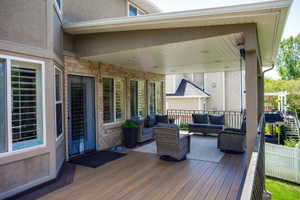 Covered outdoor deck featuring composite decking, recessed lighting, and a black metal railing