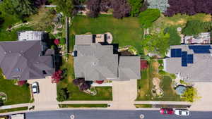 Overhead view of a property featuring a multi-gabled roof, extensive green lawn, mature trees, and a paved driveway