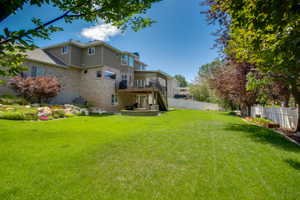 Expansive green lawn with mature trees and a multi-level deck