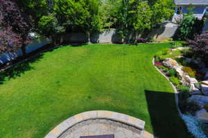 Expansive backyard featuring a manicured lawn, a built-in stone fire pit, and a rock garden with varied plantings