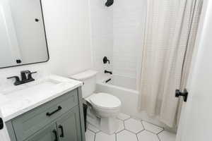 Bathroom featuring a gray vanity with a stone countertop, a rectangular undermount sink, and matte black hardware