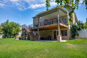 Expansive backyard featuring a large green lawn, multi-level deck with covered patio, and sturdy white privacy fencing