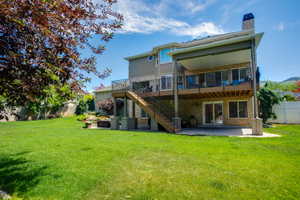 Expansive backyard featuring a manicured lawn, a two-story deck with a covered patio, and a stone fire pit area