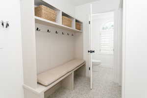 Built-in mudroom bench with upper cubbies, beadboard backing, and black hooks