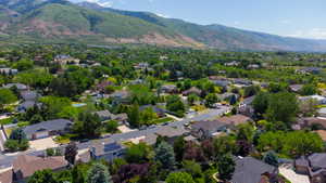 Aerial perspective showcasing a residential area with varied home styles, mature landscaping, and mountainous terrain in the background