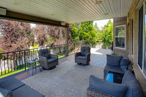 Covered outdoor deck featuring composite decking, recessed lighting, and black wrought iron railing