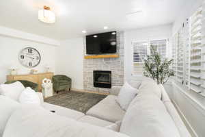 Living area featuring a stone-clad fireplace with a wood mantel, built-in television, and plantation shutters