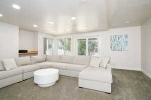 Lower level recreation room featuring recessed lighting, gray carpeting, a built-in wood shelf, and natural light from the bay window and glass-paned French doors