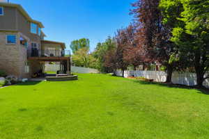 Expansive backyard featuring a large green lawn, mature trees, and a privacy fence