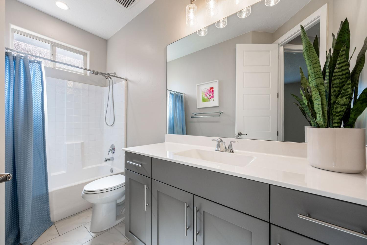 Bathroom vanity featuring a light-colored countertop, an integrated sink, and gray cabinetry with brushed nickel hardware