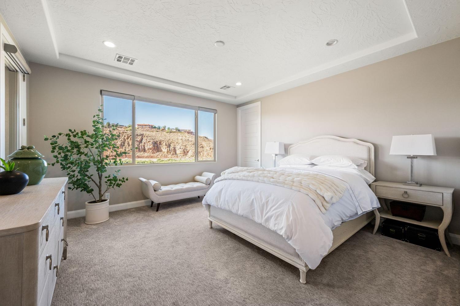 Recessed lighting illuminates a spacious room featuring a broad window with desert rock formations in the background