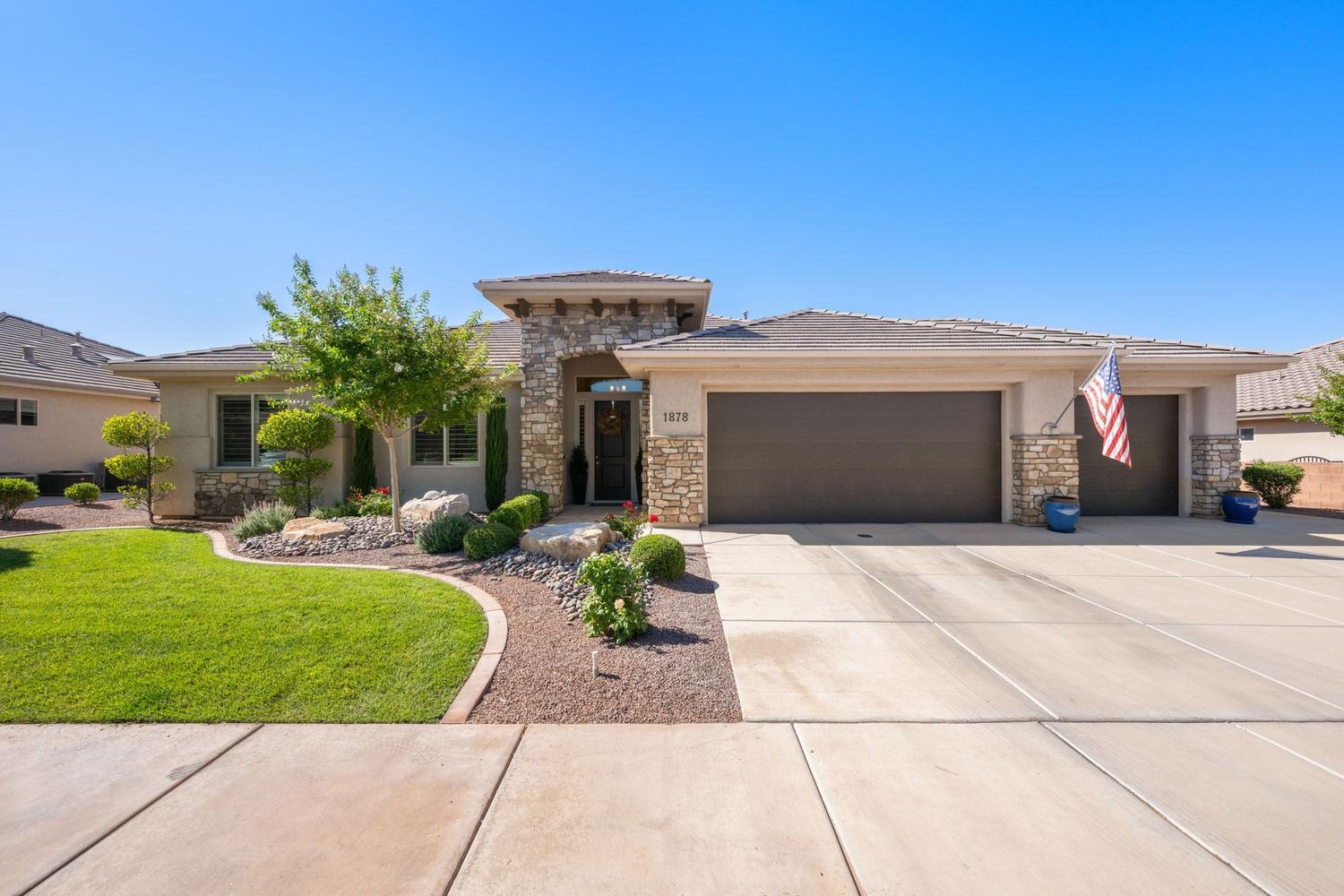Contemporary stucco and stone exterior featuring a two-car garage, a separate single-car garage, and a concrete driveway