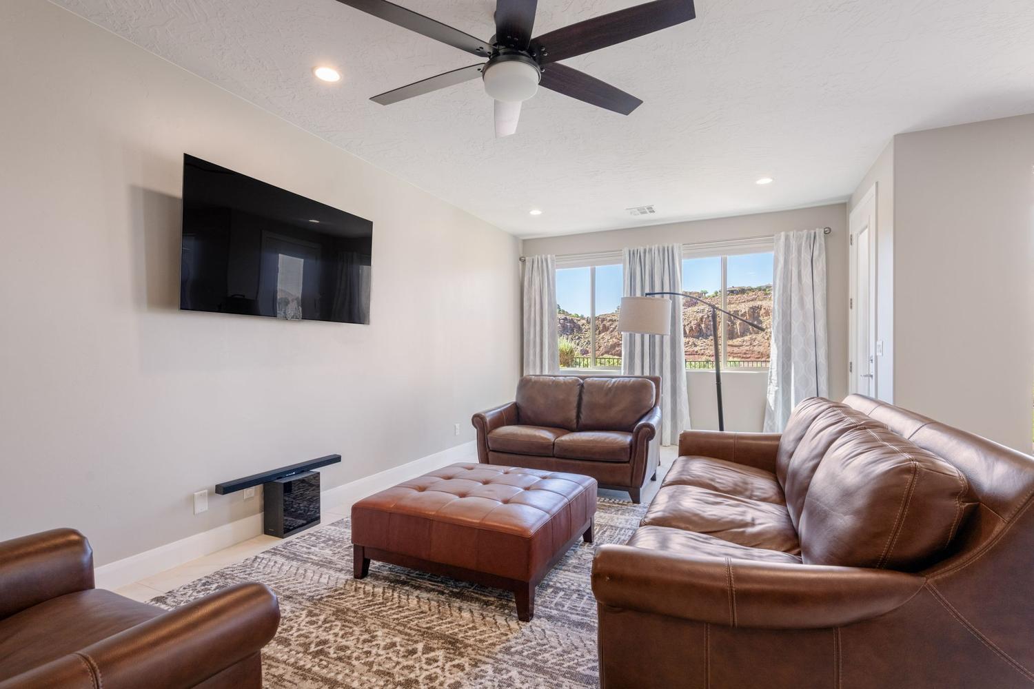 Living area with a wall-mounted television, recessed lighting, and a ceiling fan