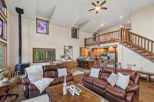 Vaulted living space featuring a wood-burning stove, rich wood-finish flooring, and multiple windows