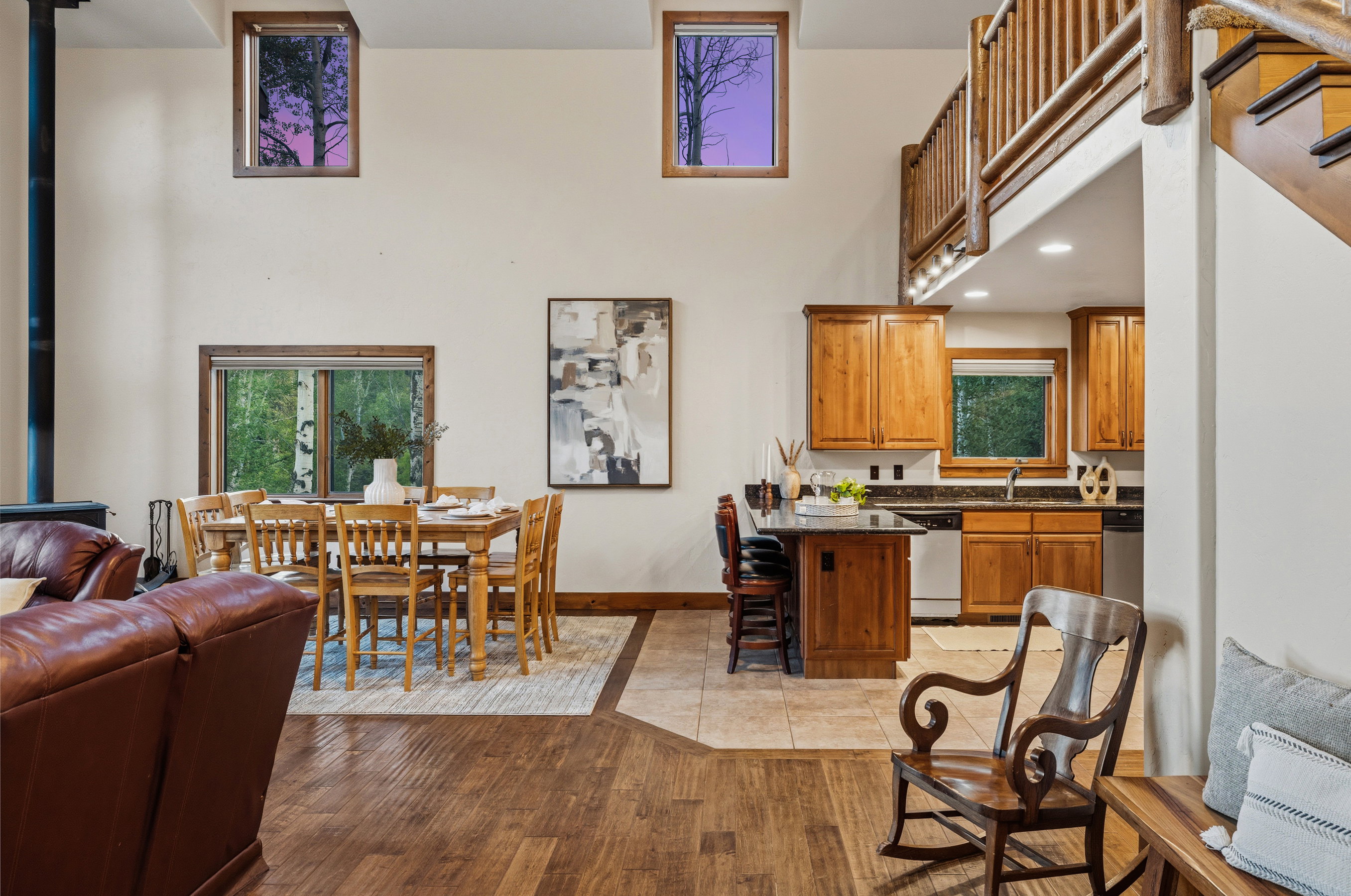 Vaulted ceiling great room featuring wood-finish flooring, a dining area, and a kitchen with wood cabinetry