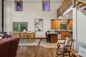 Vaulted ceiling great room featuring wood-finish flooring, a dining area, and a kitchen with wood cabinetry