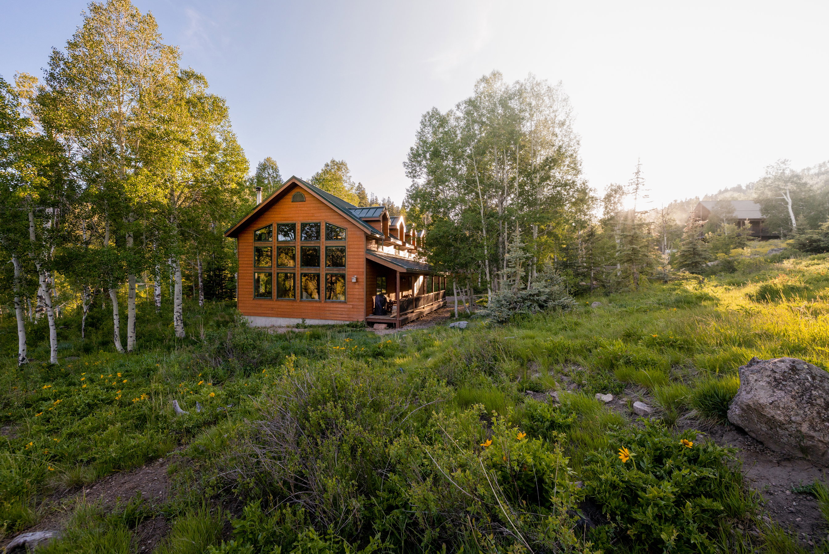Wood-sided cabin featuring a striking wall of multi-pane windows and a covered front porch