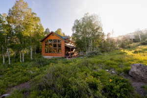 Wood-sided cabin featuring a striking wall of multi-pane windows and a covered front porch