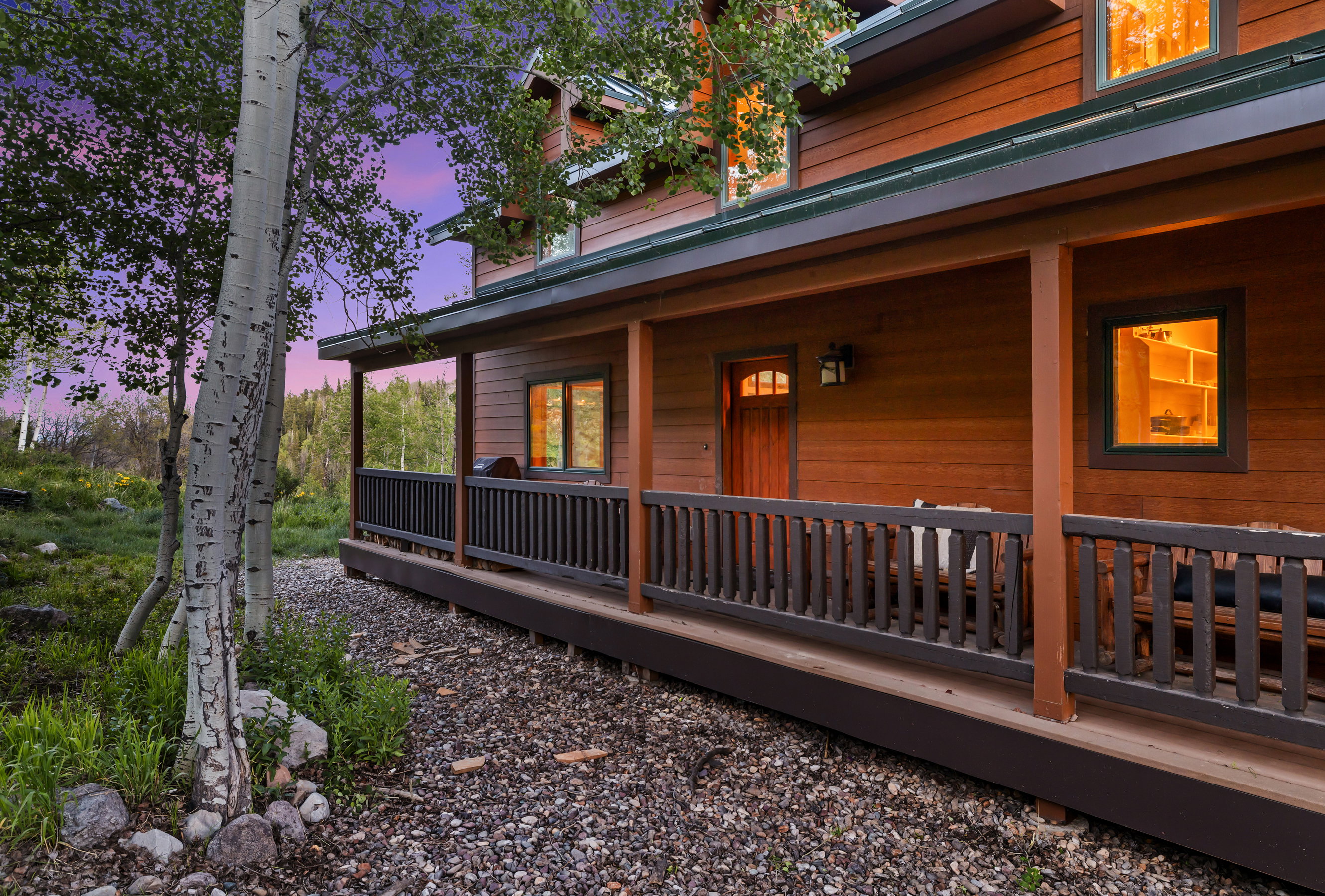 Wood-sided exterior featuring an expansive covered porch with dark wood railings and posts