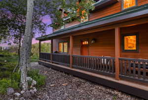 Wood-sided exterior featuring an expansive covered porch with dark wood railings and posts