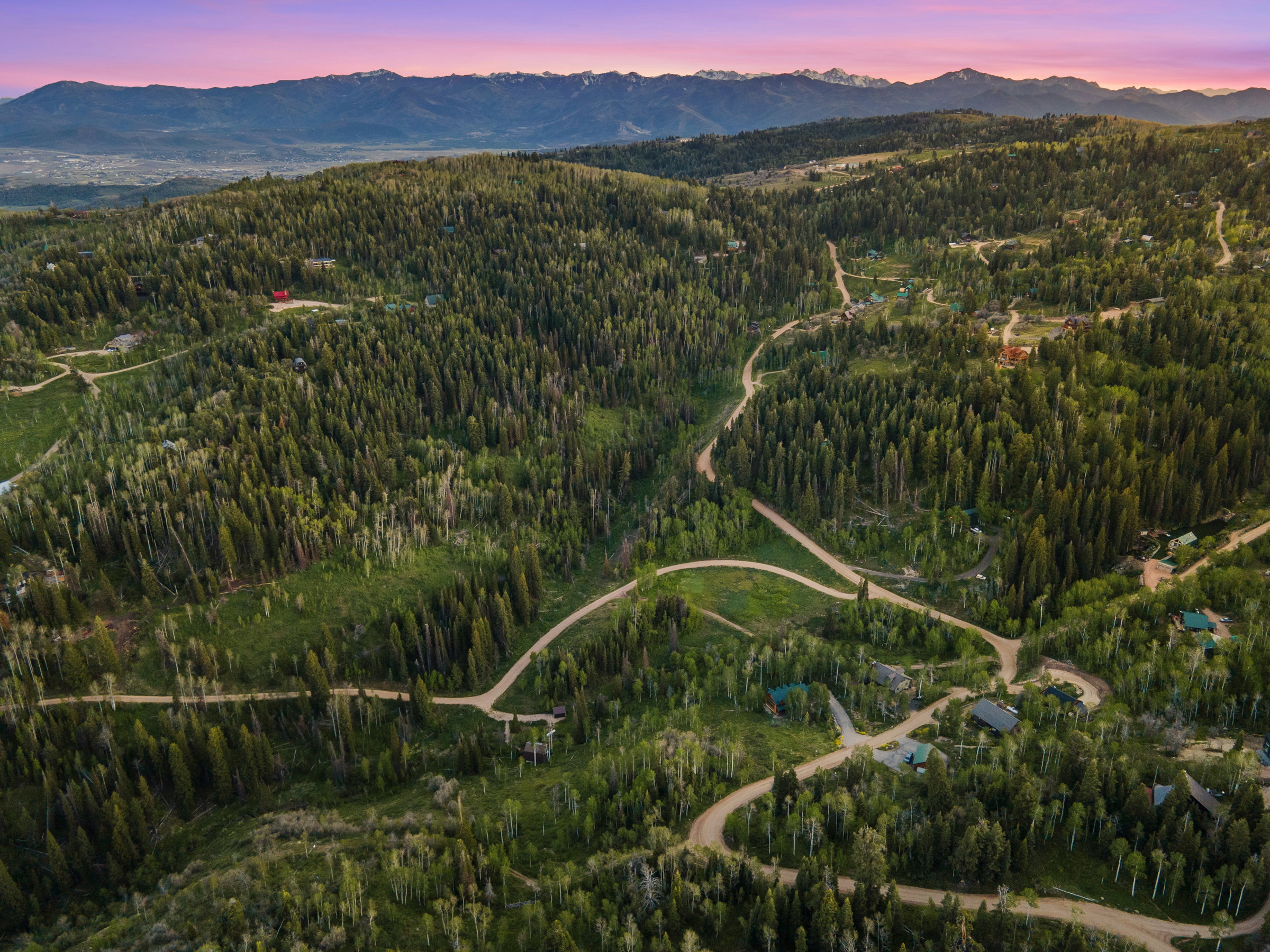 Expansive mountainous landscape featuring dense evergreen forests and scattered residential properties
