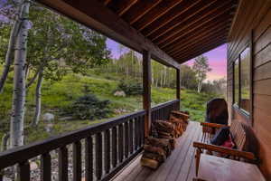 Covered porch featuring wood flooring, wood railing, and a wood ceiling with exposed beams