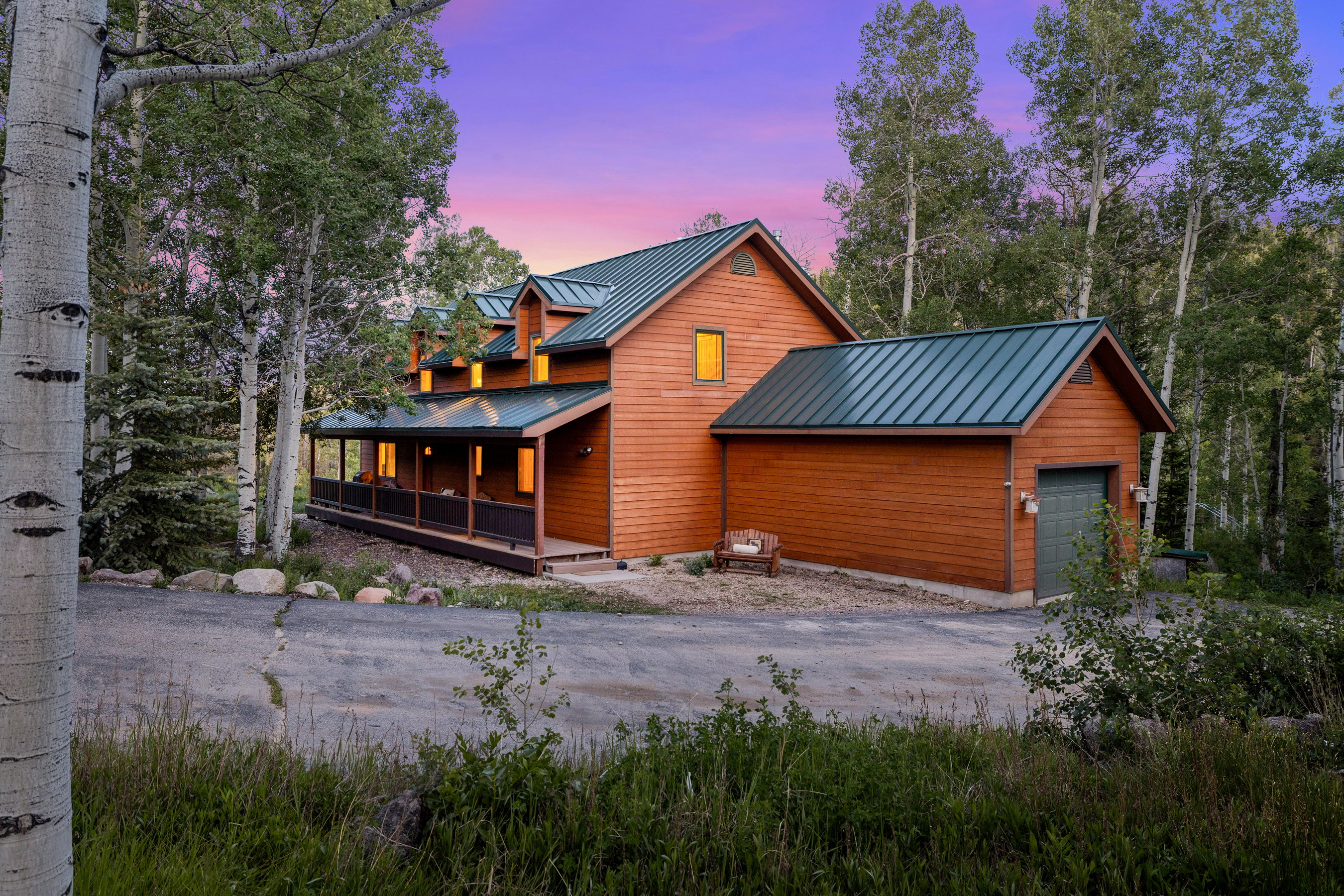 Wood-sided property featuring a green metal roof and a covered front porch