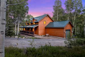 Wood-sided property featuring a green metal roof and a covered front porch