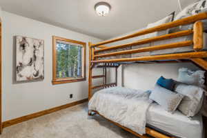 Bedroom featuring a rustic log bunk bed frame, a single window with wood trim, and wall-to-wall carpeting