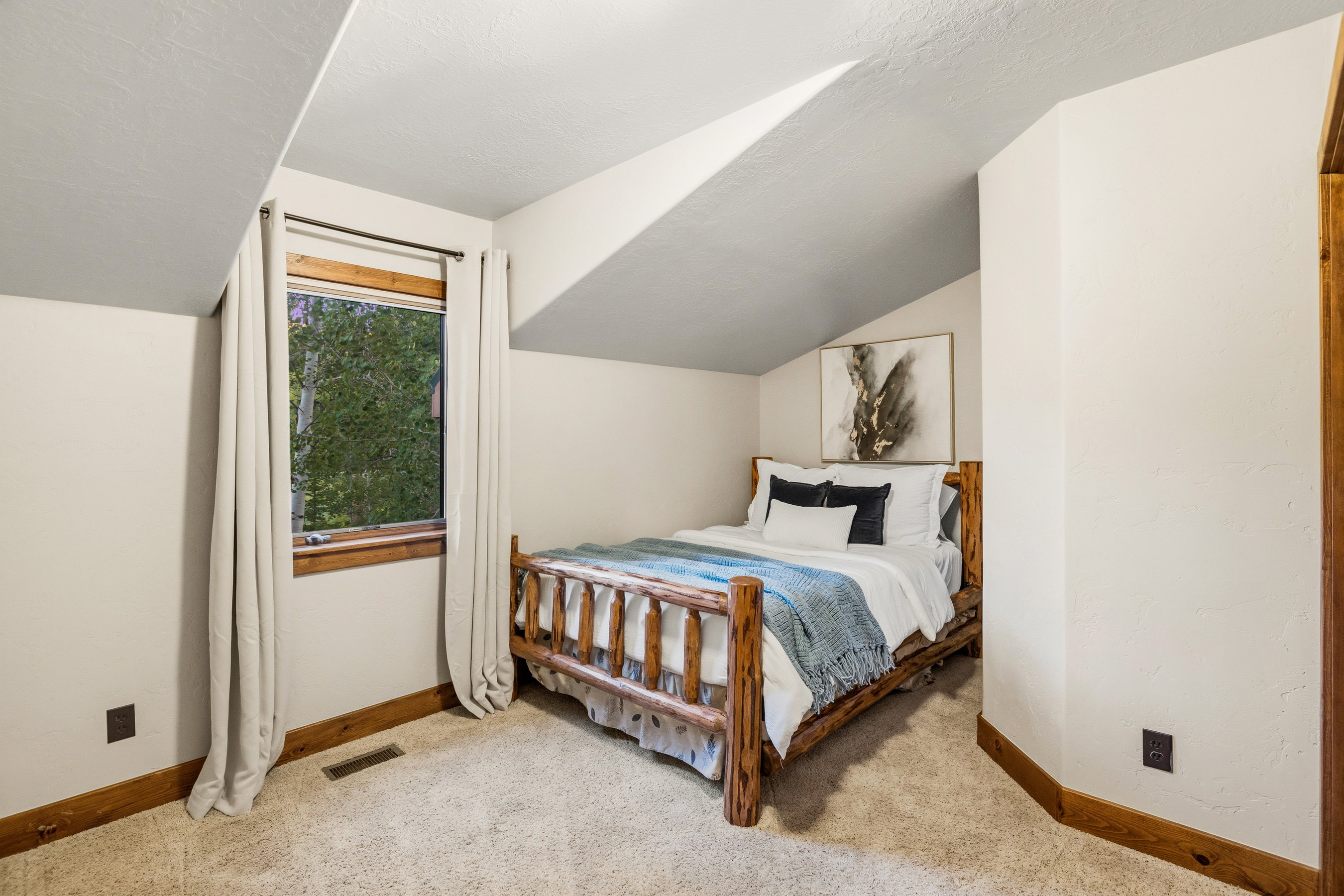 Carpeted room featuring a window with wood trim, sloped ceiling, and wood baseboards