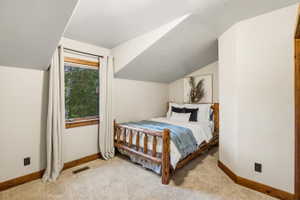 Carpeted room featuring a window with wood trim, sloped ceiling, and wood baseboards