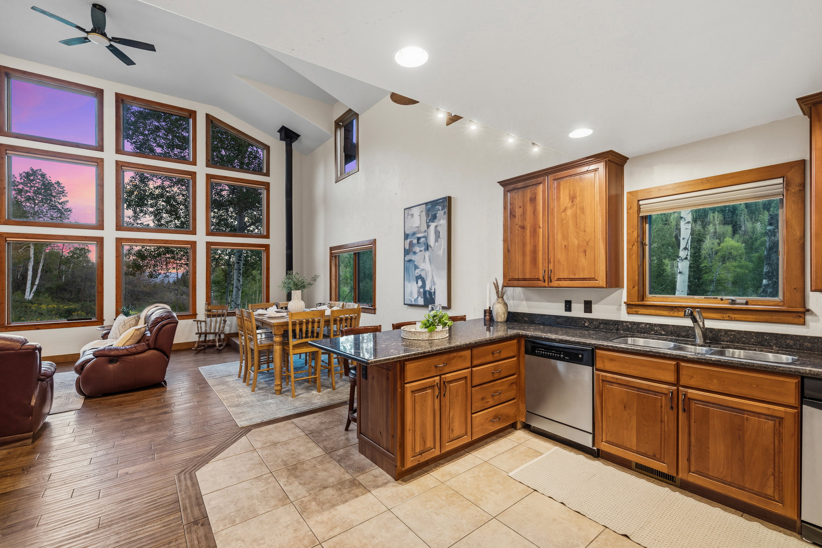 Open-concept living space featuring a high vaulted ceiling, a full wall of rectangular windows with wood framing, and wood-finish flooring