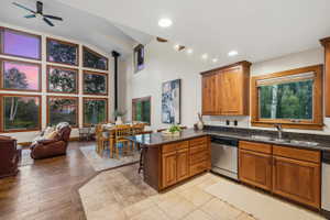Open-concept living space featuring a high vaulted ceiling, a full wall of rectangular windows with wood framing, and wood-finish flooring
