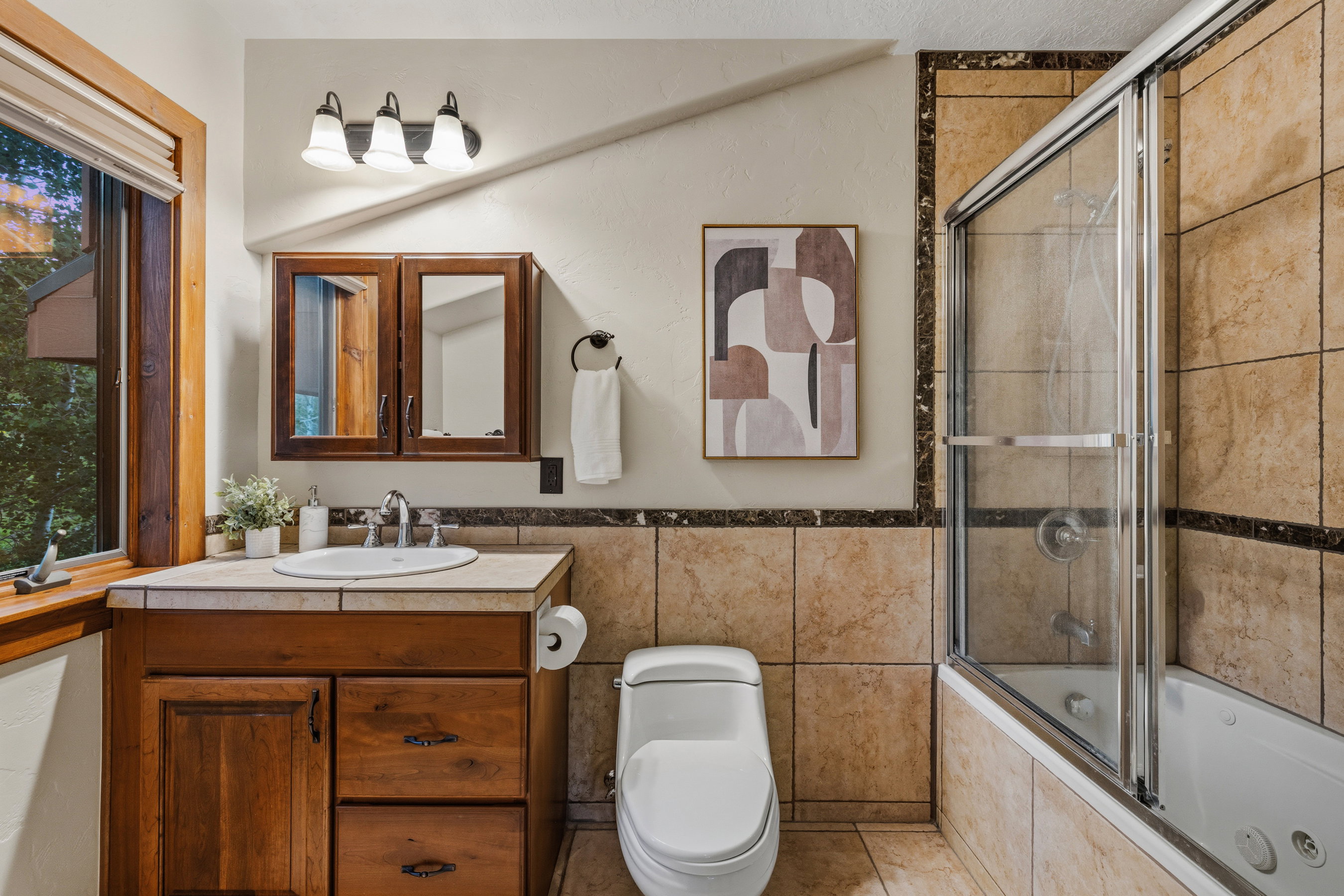 Bathroom featuring a wood-finish vanity with an undermount sink and a light-toned countertop