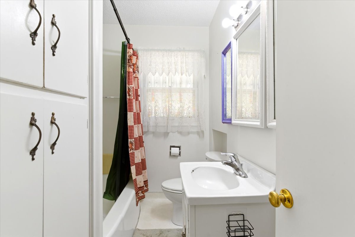 Bathroom featuring a white vanity with integrated sink, chrome faucet, and mirrored medicine cabinet