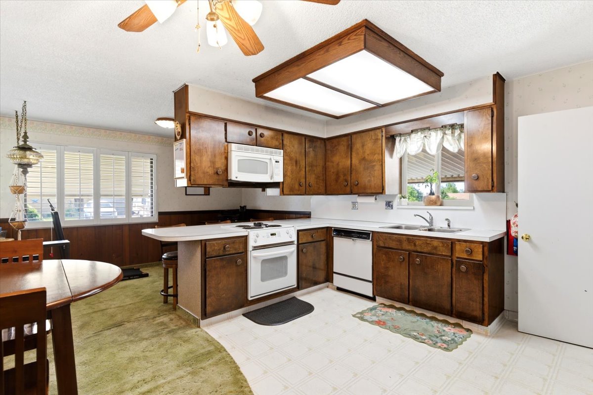 Kitchen featuring wood-finish cabinetry, white countertops, and white appliances including an oven/range, microwave, and dishwasher
