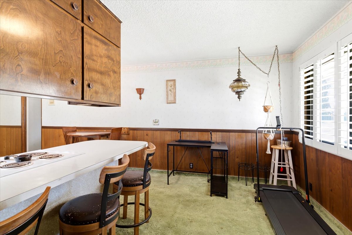 Kitchenette with wood cabinetry, white countertop with built-in cooktop, and casual bar seating