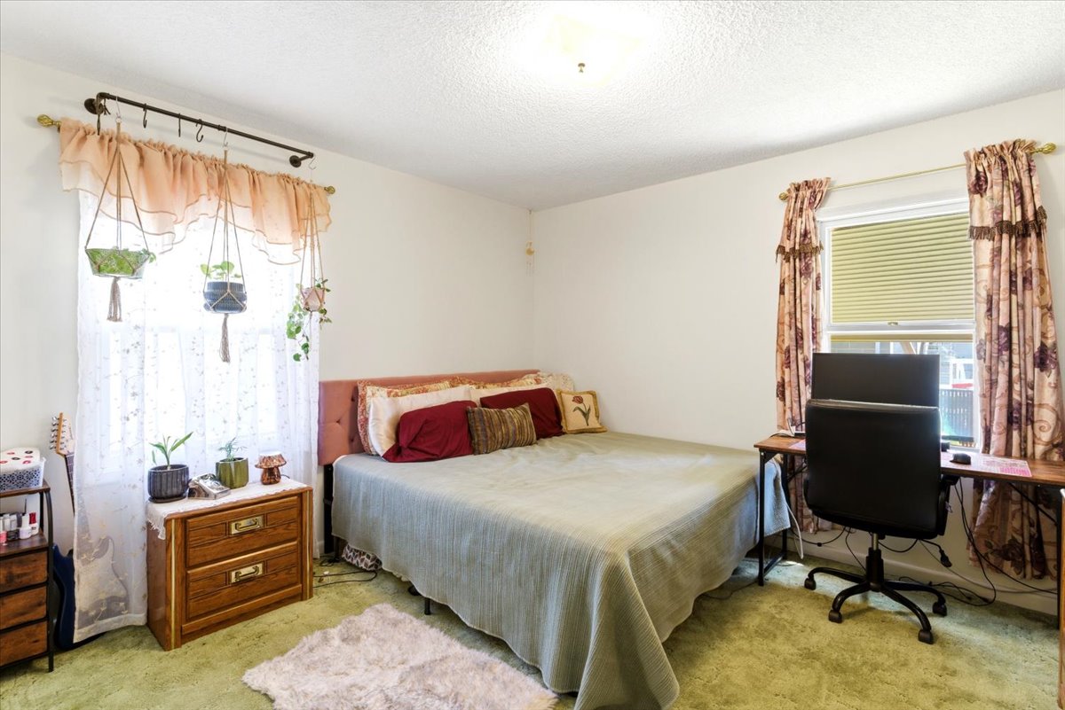 Bright bedroom featuring two windows, one with blinds