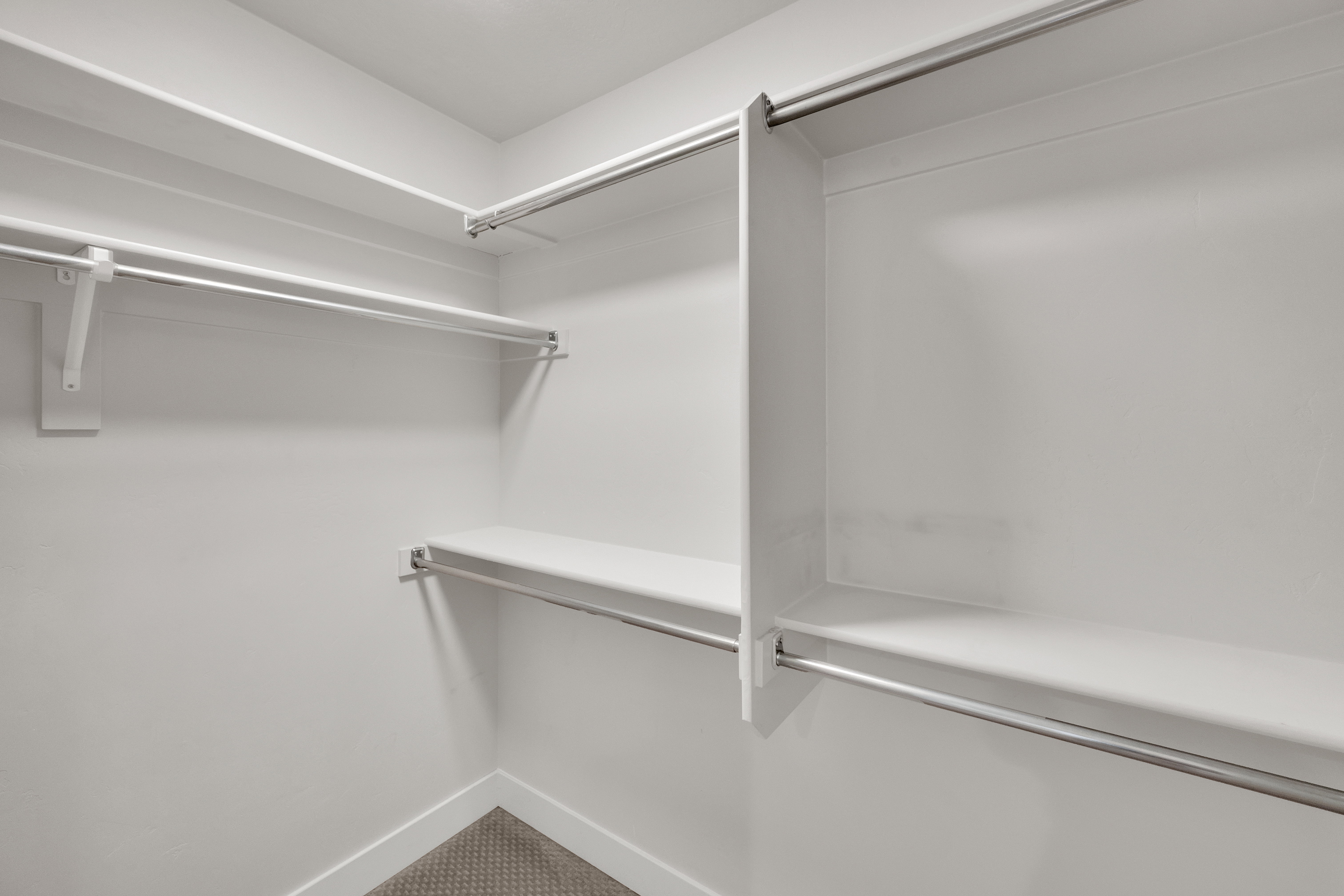 Custom closet system featuring multiple white shelves and chrome hanging rods