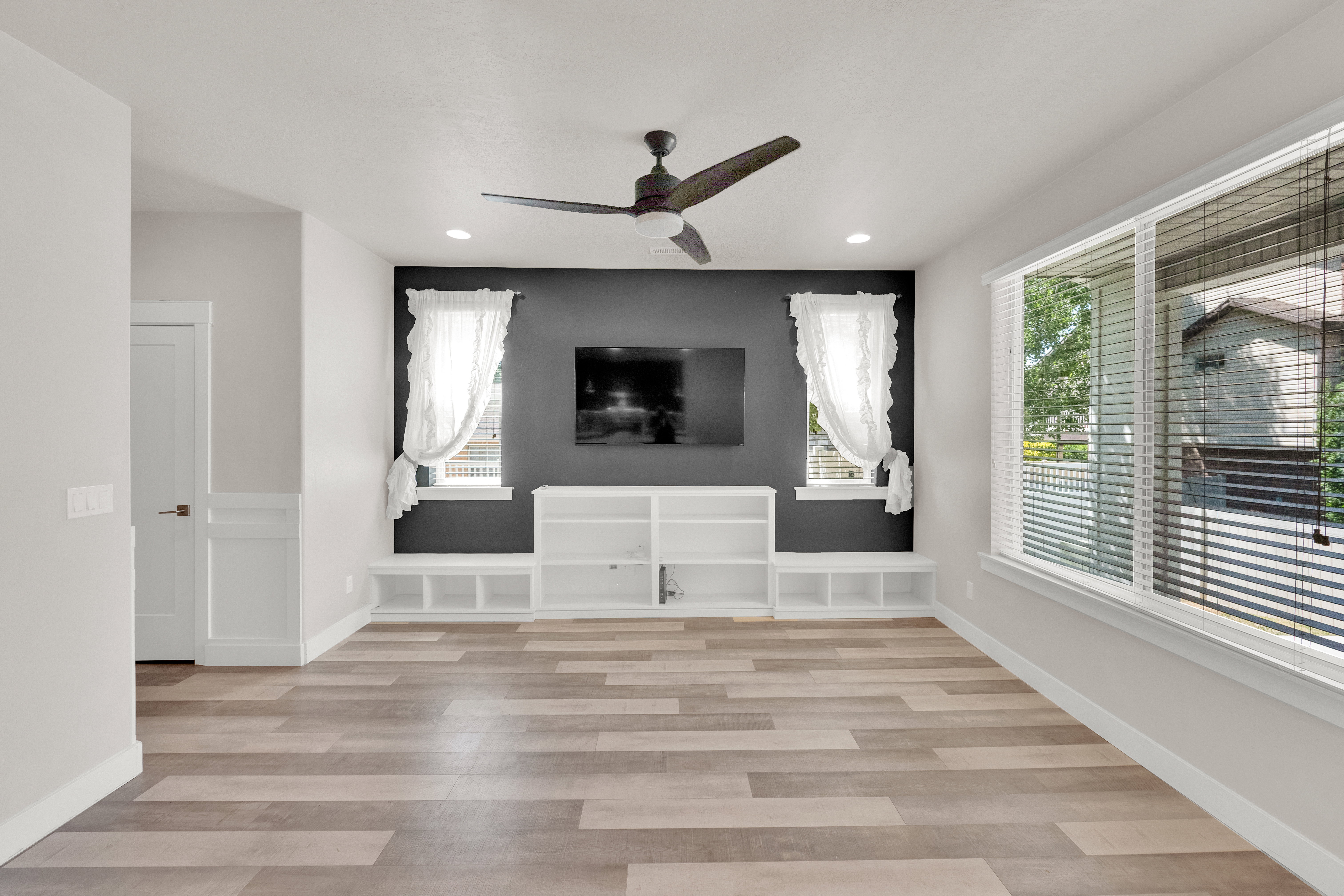 Spacious room with wood-finish flooring, a contemporary ceiling fan, and recessed lighting