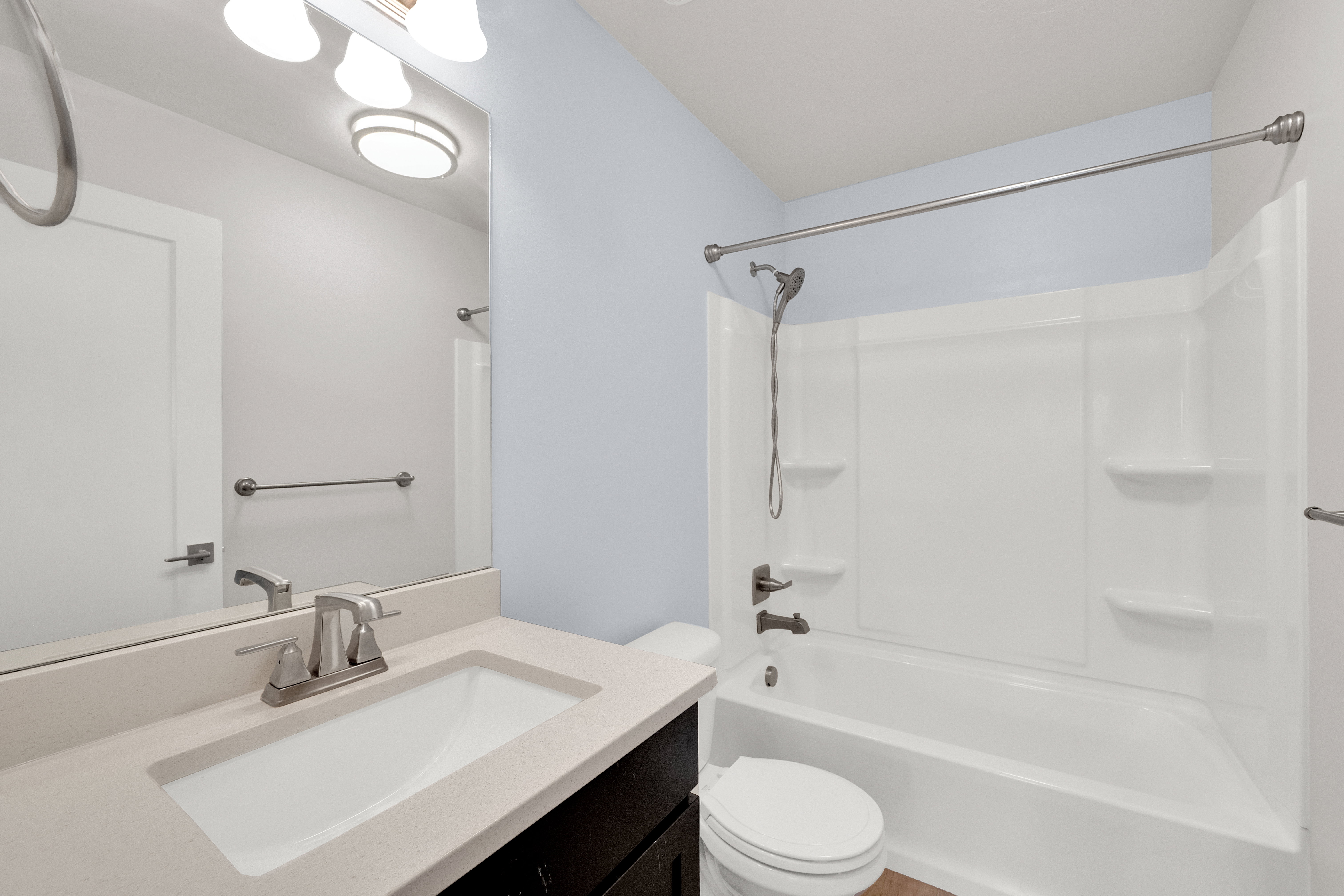 Bathroom featuring a white integrated sink, light-toned countertop, dark wood-finish vanity, and brushed nickel fixtures
