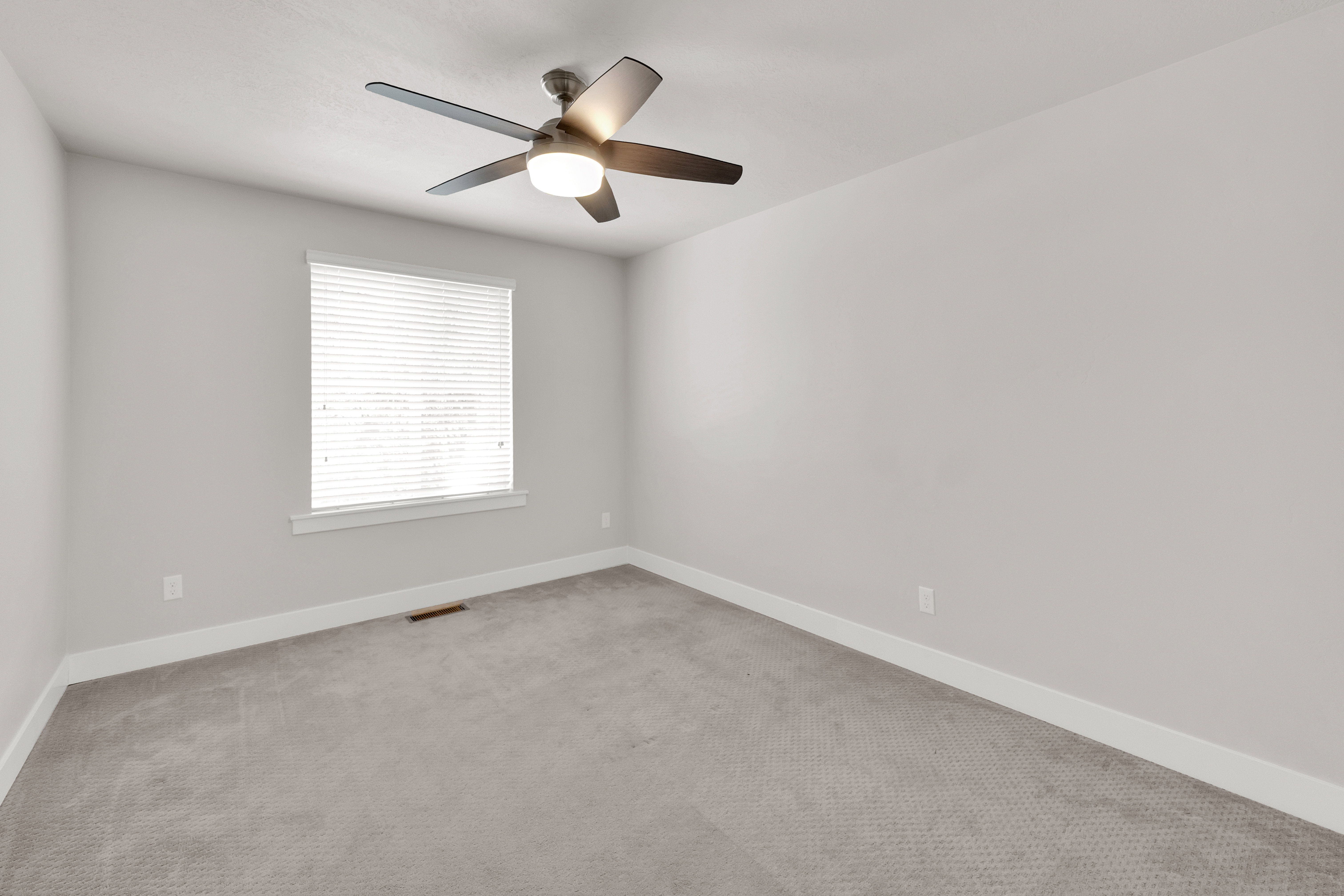Neutral wall paint, ceiling fan with integrated lighting, window with blinds, baseboard trim, and gray carpeted flooring