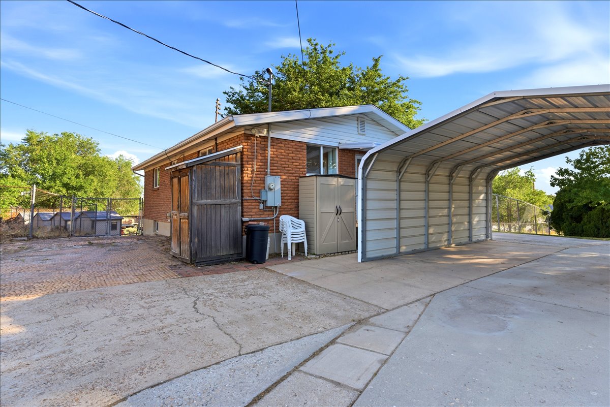 Expansive concrete driveway featuring a large metal carport structure